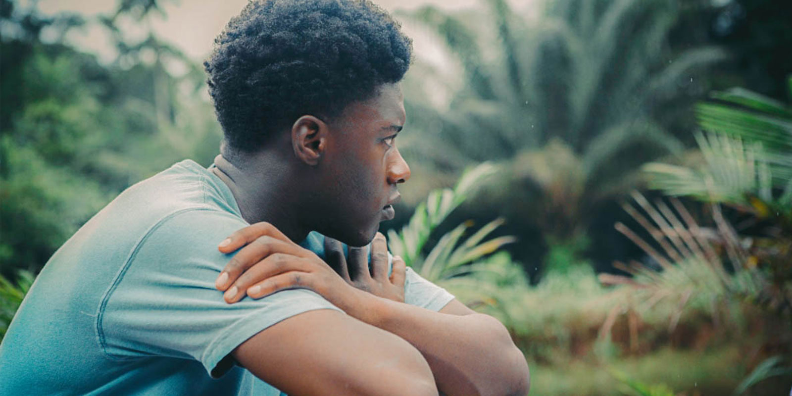 Screenshot from 'The Last Tree' directed by Shola Amoo, featuring a young actor surrounding by greenery looking off to the distance