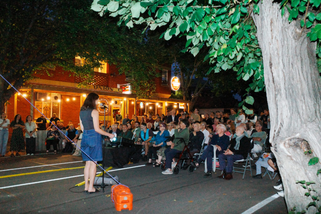 Filmmaker Zoe Coldham presenting their film to a crowd on Gore Street in Fitzroy.
